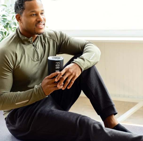 Man stretching holding a For Wellness tumbler