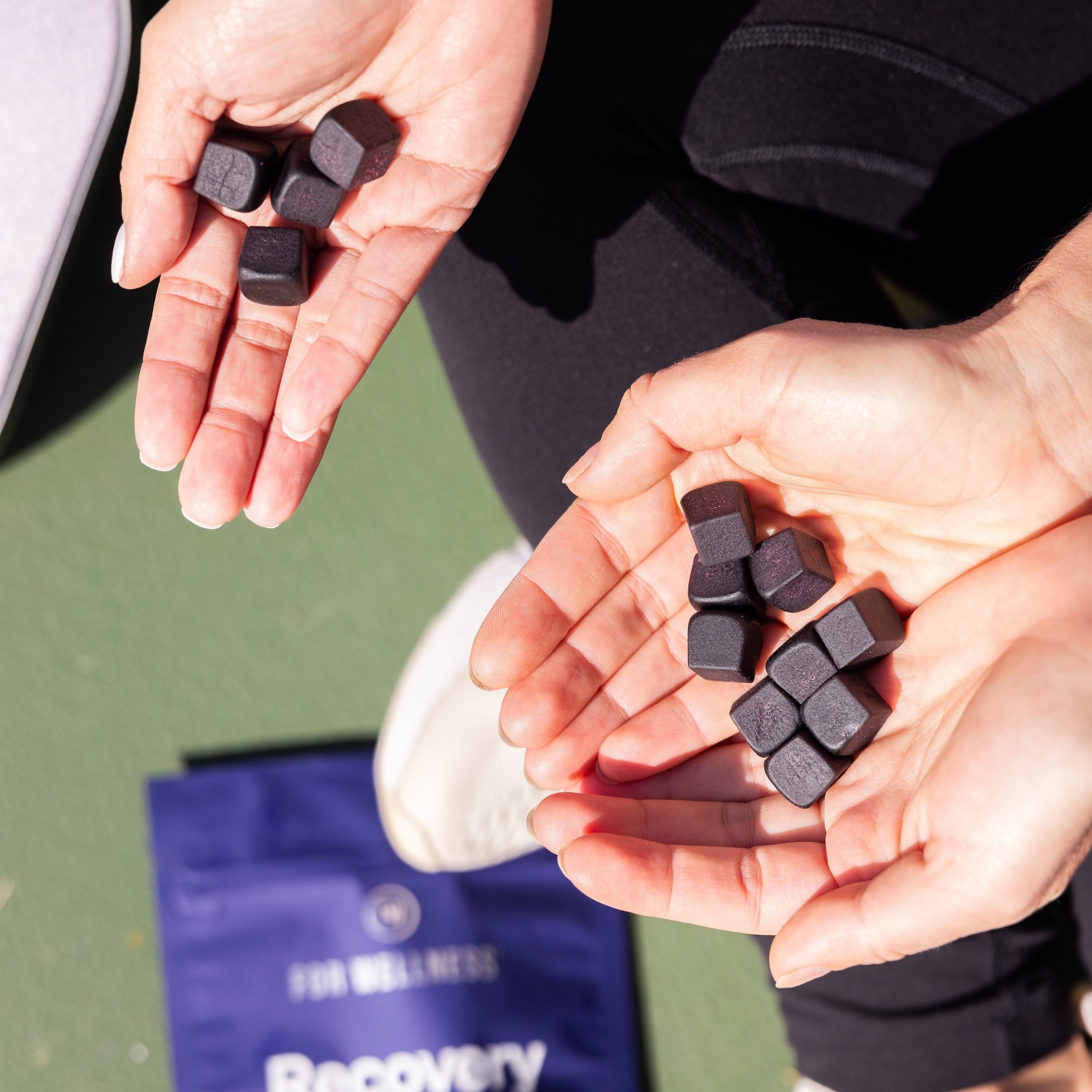 Two hands holding a bunch of Recovery Gummies hydration