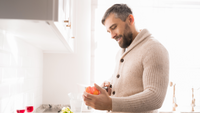 Man cutting a red pepper in a kitchen