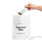 Hand pouring a packet of Superfood Bites into a white bag.