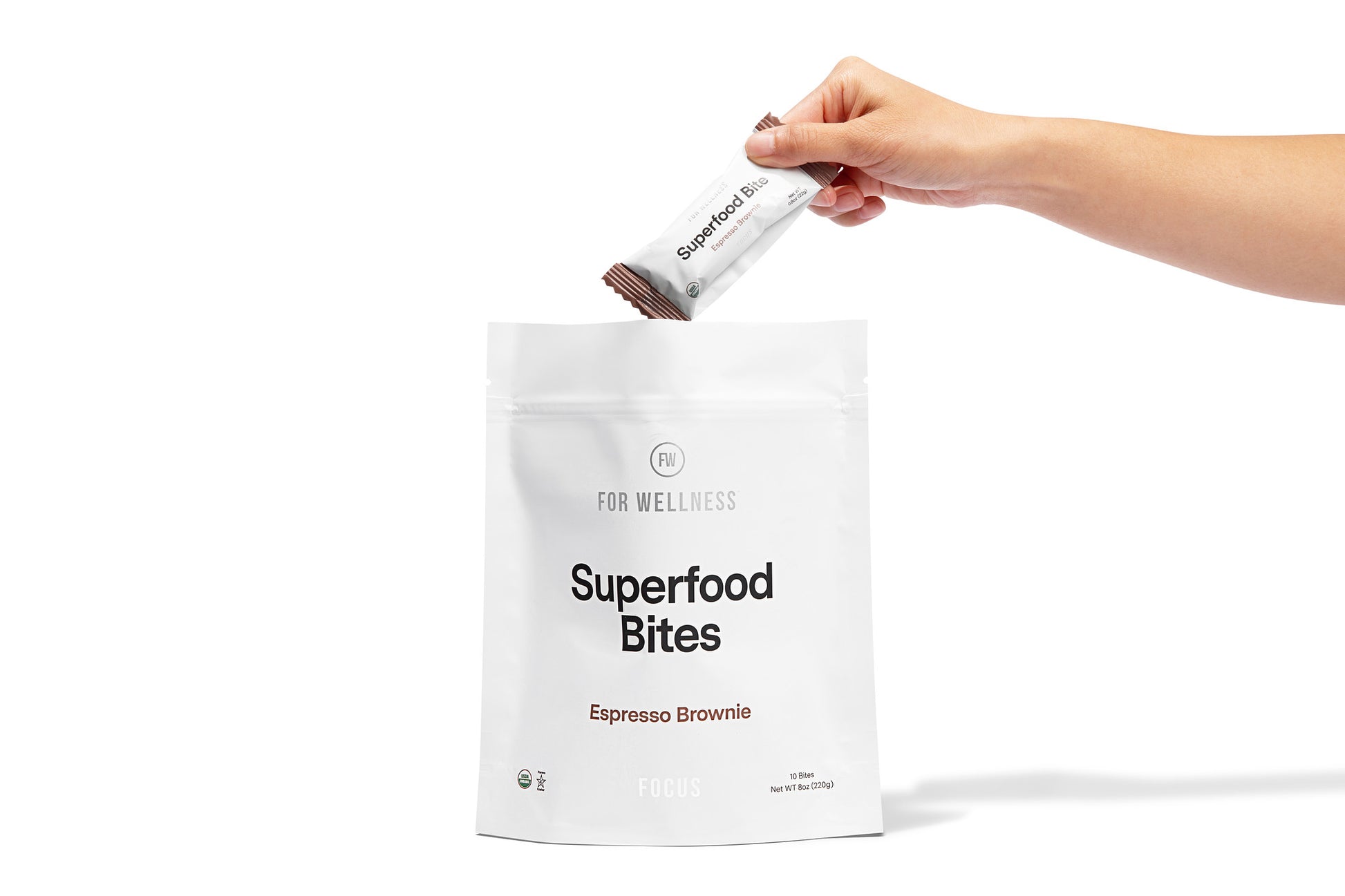 Hand pouring a packet of Superfood Bites into a white bag.