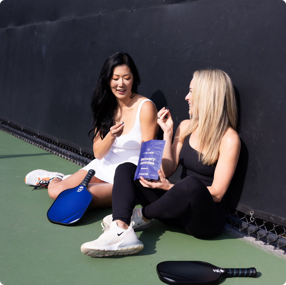 Two women sitting down enjoying the Recovery Gummies Hydration after a game of pickelball 