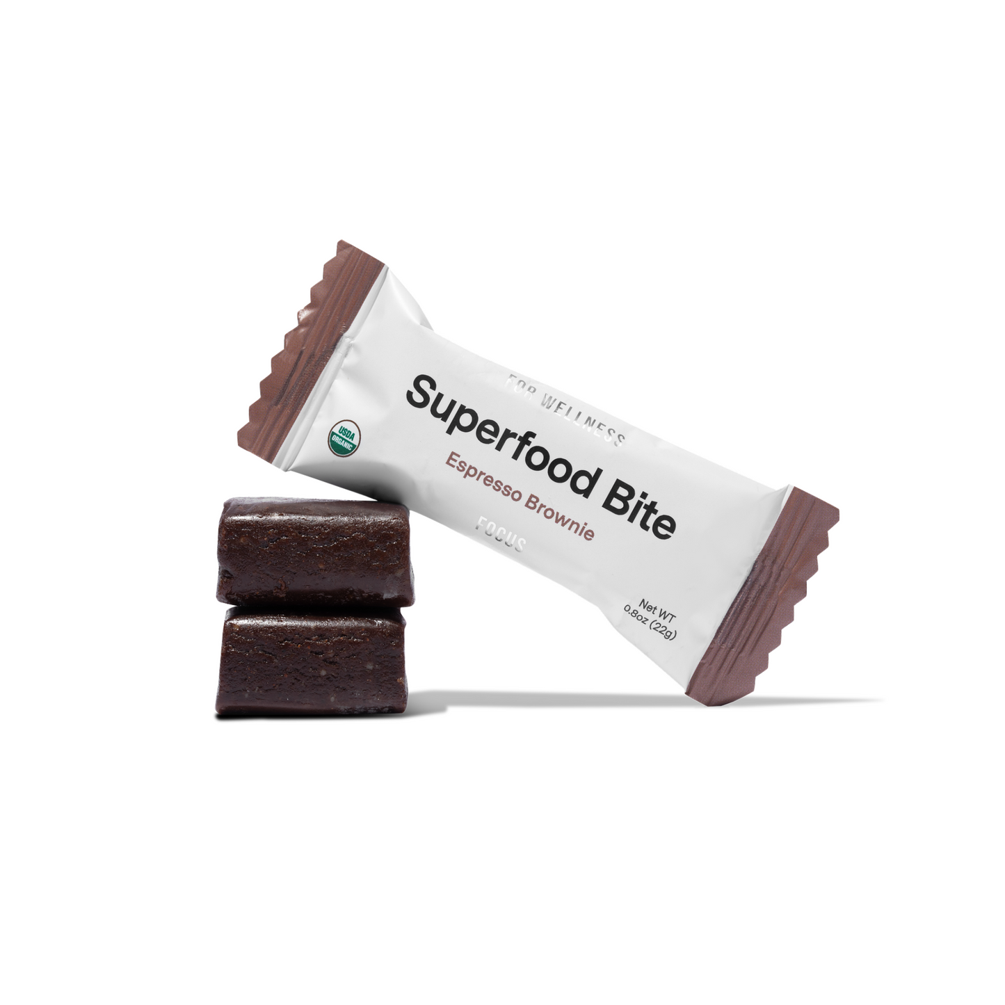 Unwrapped Superfood Bites stacked on top of each other with a wrapped bite resting against them 