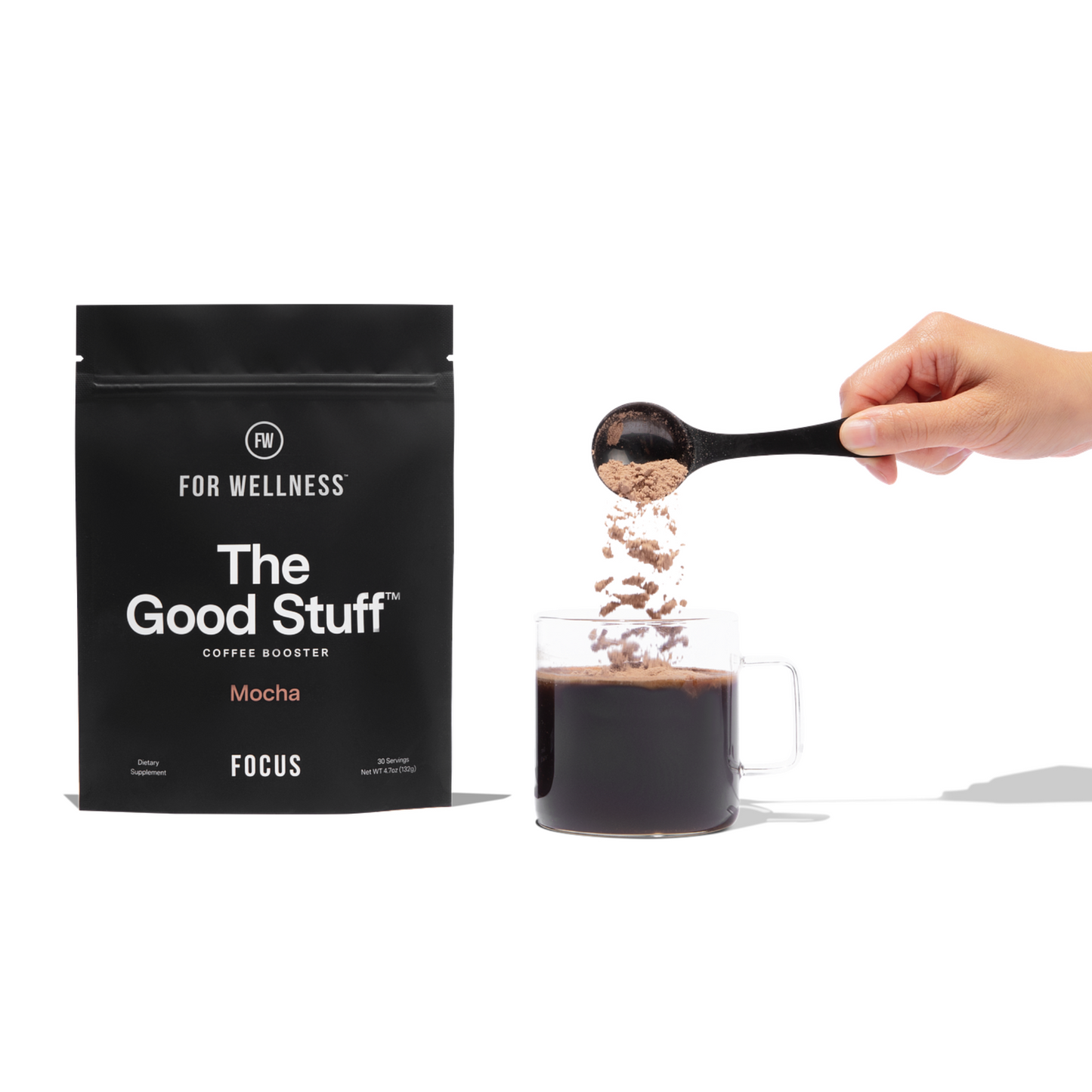 Hand pouring The Good Stuff Focus into cup of coffee next to pouch of Good Stuff Focus