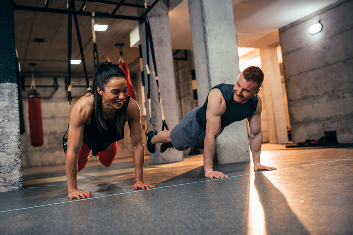 Photo of man and woman doing pushups in a gym